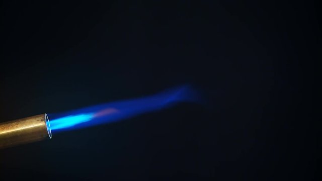 Butane gas burner flame burning from nozzle against black background