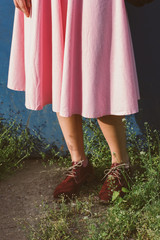 Close up of beautiful legs in shoes and pink dress of a young woman