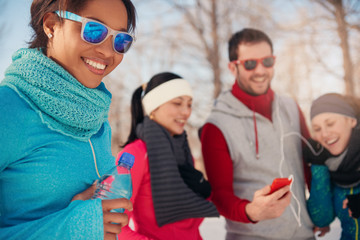Group of friends listening to music in the snow in winter
