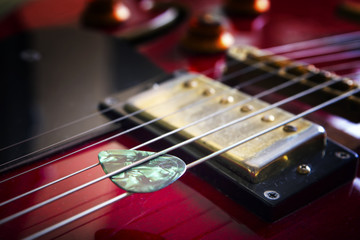 Fototapeta na wymiar Red acoustic guitar with plectrum close up in dark background