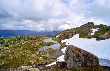 Over cast at the mountain top of Stordalsnippa in Norway, with the last summer snow melting in to a pond