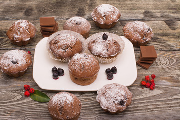 cupcake with berries on a white plate, wooden background