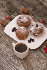cupcake with berries on a white plate, small white cup of coffee, wooden background