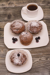 cupcake with berries on a white plate, small white cup of coffee, wooden background