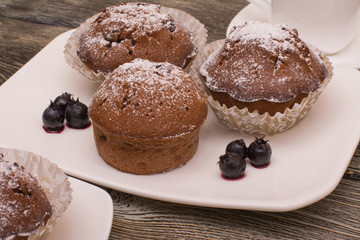 cupcake with berries on a white plate, small white cup of coffee, wooden background