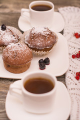 cupcake with berries on a white plate, small white cup of coffee, wooden background