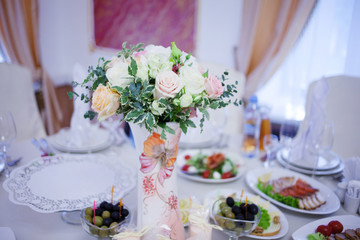 Wedding floristry. Beautiful lush bouquet on the table in restaurant. Table served food and snacks