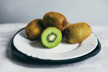 A pile of ripe kiwi on a white plate - 123344992