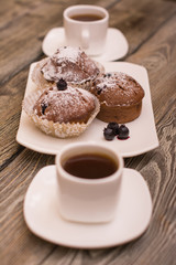 cupcake with berries on a white plate, small white cup of coffee, wooden background