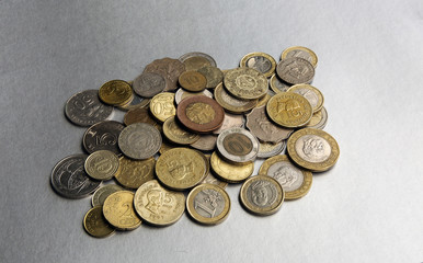 lPile of coins from different countries on a silver background.
