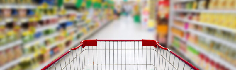 supermarket aisle with empty red shopping cart