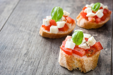 Caprese salad bruschettas isolated on wooden table

