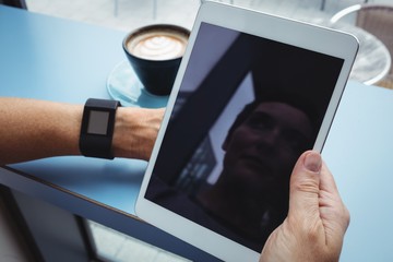 Businesswoman using digital tablet while having coffee
