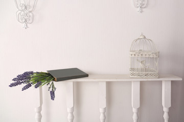 Book with flowers and a bird cage in the room on a shelf
