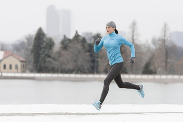 Woman Running through Denver City Park in Winter with Boathouse and Snow in Background