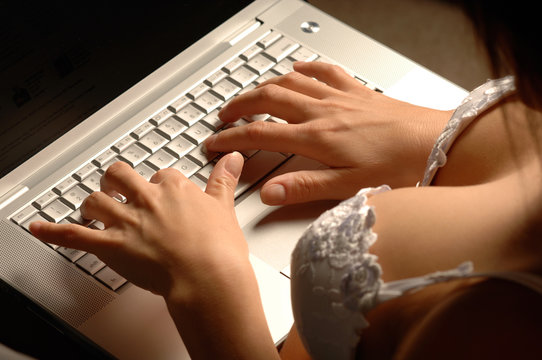 Stunning over-the-shoulder woman in bra underwear typing on laptop computer