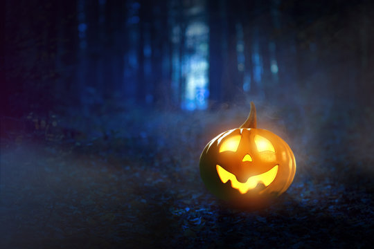 Leuchtender Halloween-Kürbis im nebeligen Wald