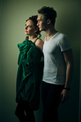 Boy in white t-shirt stands behind gorgeous woman in dark green