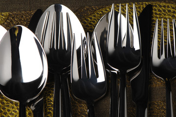 Shining silverware flatware cutlery knives forks and spoons on green place mat before setting...