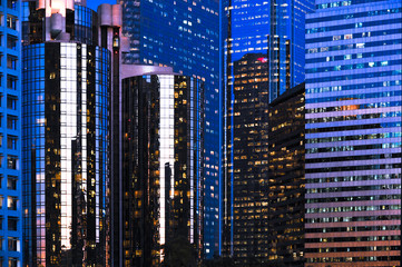 Mirrored downtown Los Angeles skyscrapers reflecting deep blue twilight sky with lighted windows