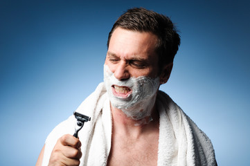 Man snarling at razor with shaving cream and towel