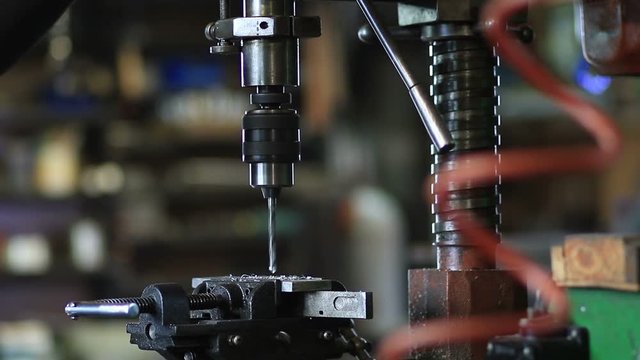Man drilling in steel plate with bench drill
