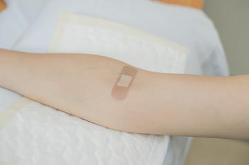 putting adhesive bandage on arm