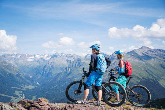 Two women standing with mountain bikes in Swiss Alps, Davos, Graubunden, Switzerland