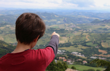 Fototapeta na wymiar boy shows the beautiful landscape of the italian Apennines