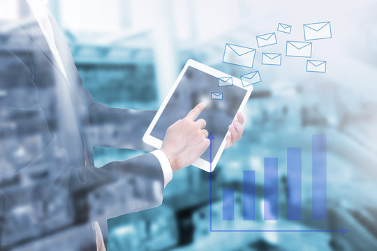 Double exposure of businessman using the tablet to send email with business graph on blur image of building , globalization smart business concept