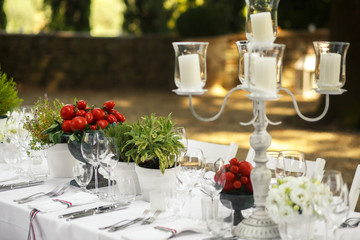 Vases with cherry tomatoes stand on the dinner table among glass