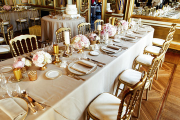 Wooden chairs with white seats stand at the rich dinner table