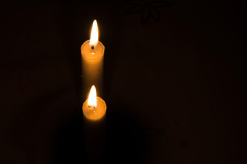Two burning candles on black background. Copyspace