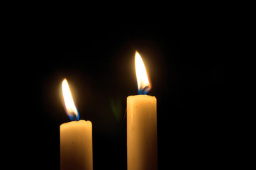 Two burning candles on black background. Copyspace