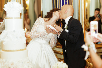 Bride kisses groom after tasting wedding cake from his hands