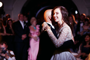 Laughing bride holds groom tender standing in the middle of danc