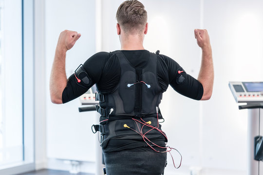 Man in EMS suit training his back in electro muscle stimulation gym