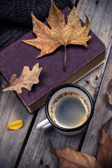Old book, knitted sweater with autumn leaves and coffee mug
