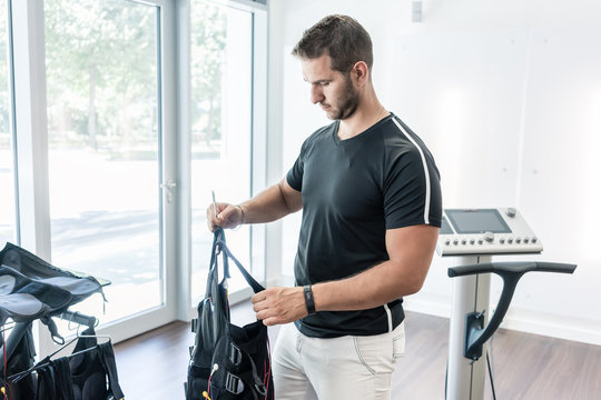 Trainer in EMS Gym putting away vests after training