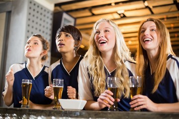 Female fan watching football at bar counter
