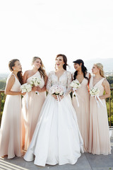 Bridesmaids in peach dresses surround gorgeous bride on the balc