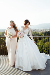 Fototapeta na wymiar Blonde bridesmaid stands behind pretty bride in marvelous weddin