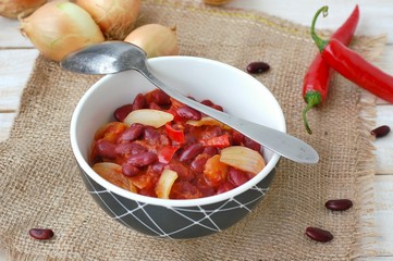 Mexican chili beans with onion, green pepper on the gunny cloth on wooden background