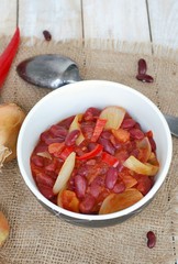 Mexican chili beans with onion, green pepper on the gunny cloth on wooden background