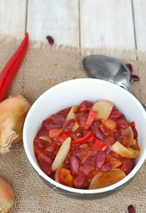 Mexican chili beans with onion, green pepper on the gunny cloth on wooden background