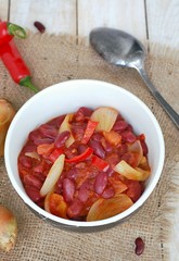 Mexican chili beans with onion, green pepper on the gunny cloth on wooden background