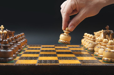 Male hand moving white pawn at the beginning of chess game.