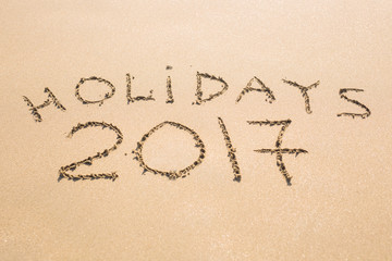 Happy Holidays 2017. Written in sand at the beach. Holiday, Christmas, New Year 2017 concept.