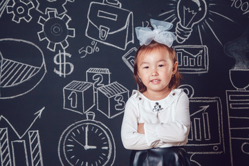 Little smart girl standing and folded hands on dark background with business or school picture