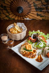 Grilled chicken steak with lettuce salad cherry tomatoes mushrooms herbs  on  white plate and wooden background. Traditional cuisine. Grill kitchen.